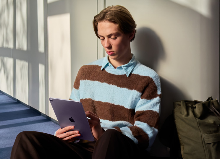 Iemand die op de vloer zit in een lichte ruimte en iPad met Apple Pencil gebruikt.