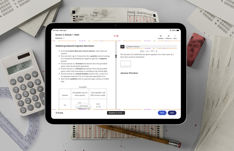 Um iPad está sobre uma mesa, entre formulários de prova impressos e materiais escolares Na tela, aparecem instruções para concluir a parte de matemática de um teste padronizado